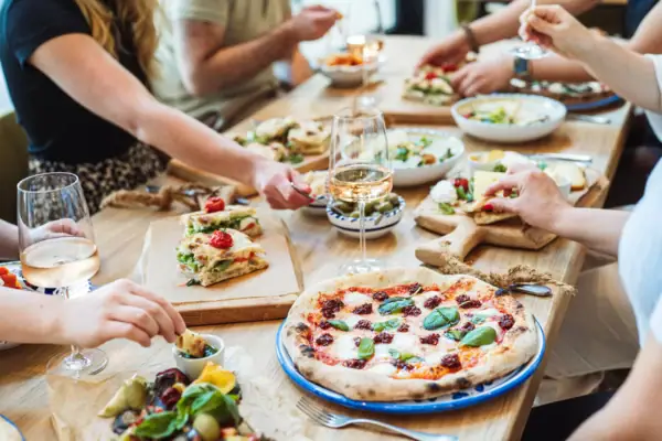Italienische Spezialitäten im A-ROSA Gardasee Festlich gedeckter Tisch mit italienischen Speisen, Pizza und Antipasti in geselliger Runde.