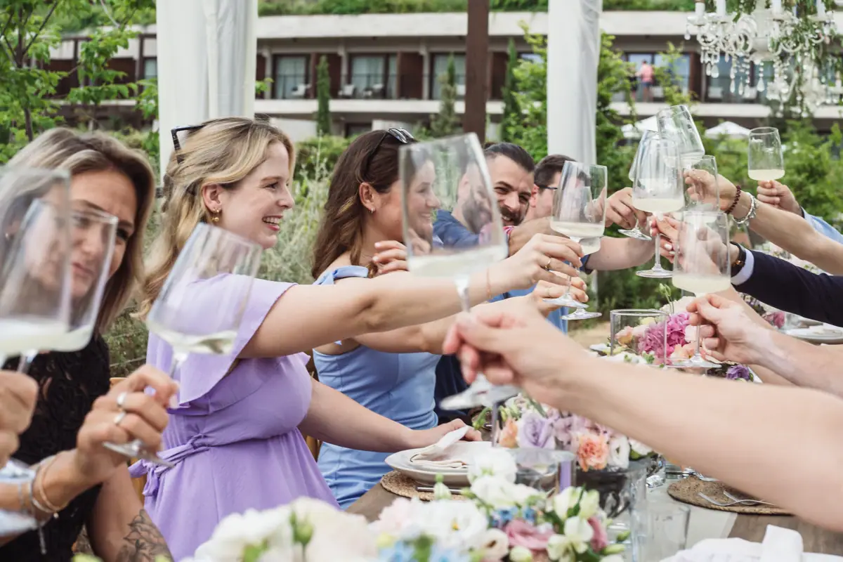 Fröhliche Stimmung beim Anstoßen im Garten des A-ROSA Gardasee Gäste stoßen bei einer privaten Feier im Garten des A-ROSA Gardasee mit Sektgläsern an, umgeben von festlich dekorierten Tischen.
