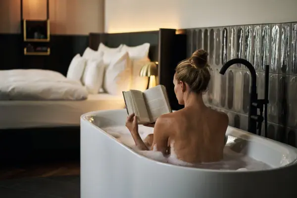 A woman is reading a book in a bath.