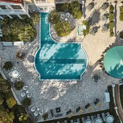 Pool surrounded by chairs and trees.