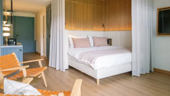 Elegant bedroom featuring a plush bed with white curtains and soft linens in a boutique hotel setting.