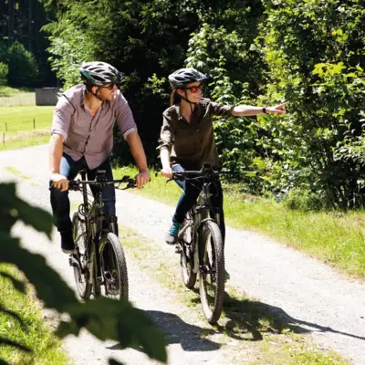 A man and a woman are cycling along a path.