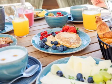 A lavishly laid breakfast table with pancakes and fresh berries in the middle.