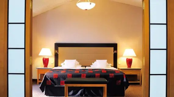 Bed with black and red blanket in a hotel room.