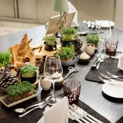 A table set with plants and glasses.