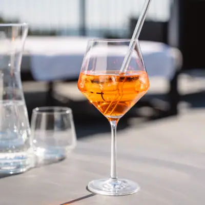 A glass with orange liquid and ice on a table.