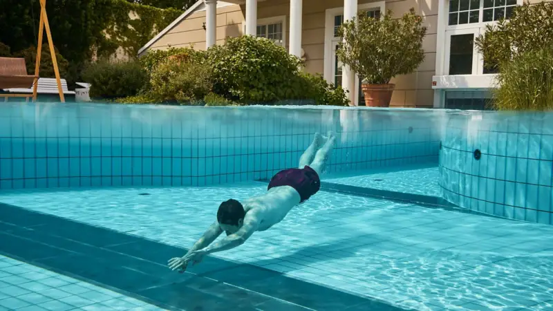 Man swimming in an outdoor pool.