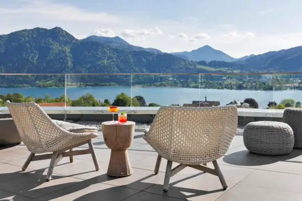 A table and chairs on a terrace overlooking a body of water.