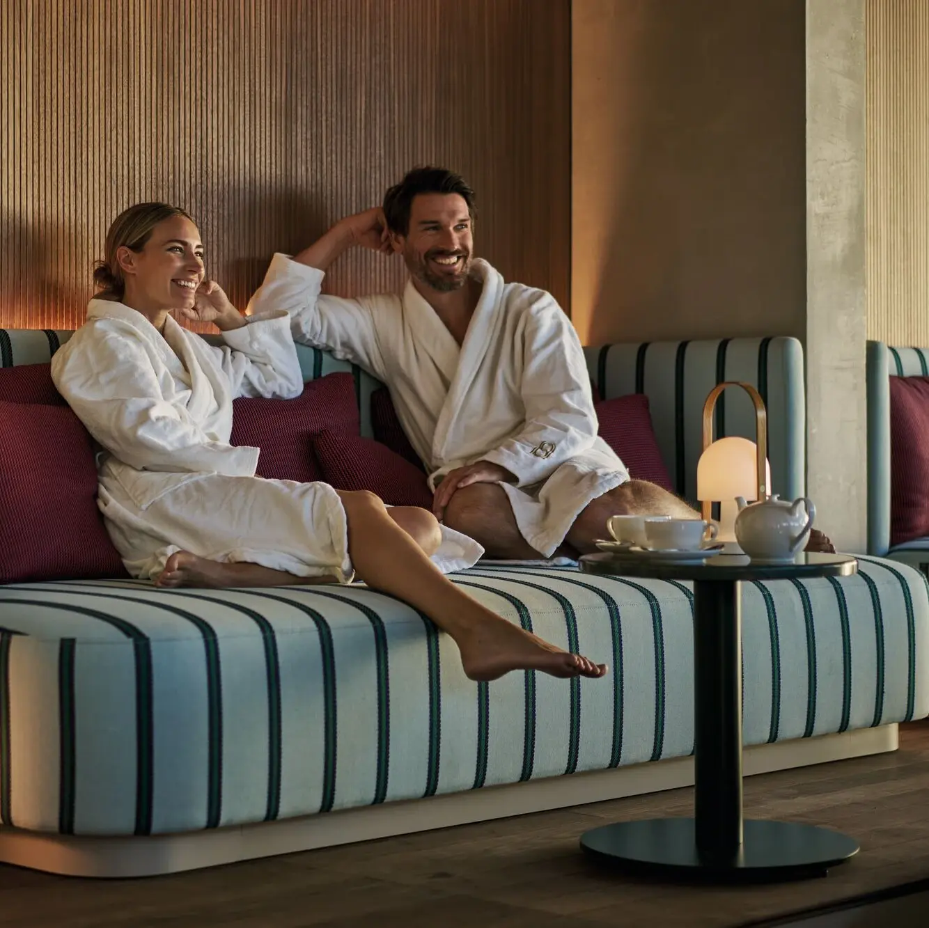 Couple in bathrobes relaxing at the Straubinger Grand Hotel spa lounge in Bad Gastein with tea service.