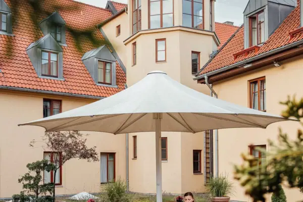Eine Frau sitzt an einem Tisch unter einem Sonnenschirm im Innenhof.