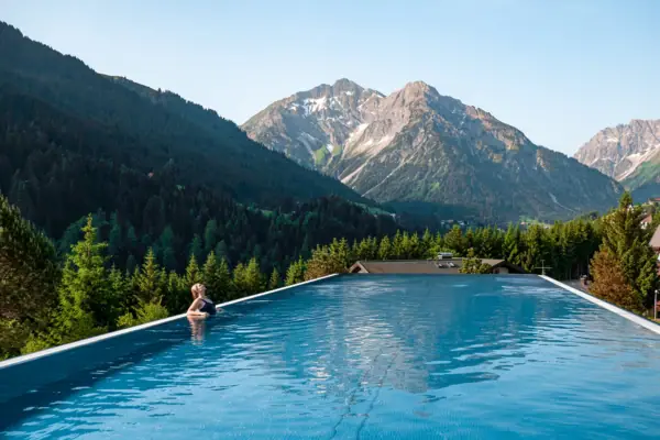 A person in a swimming pool with mountains in the background.