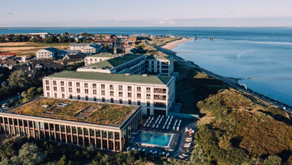 An aerial view of a building with a pool by the beach.