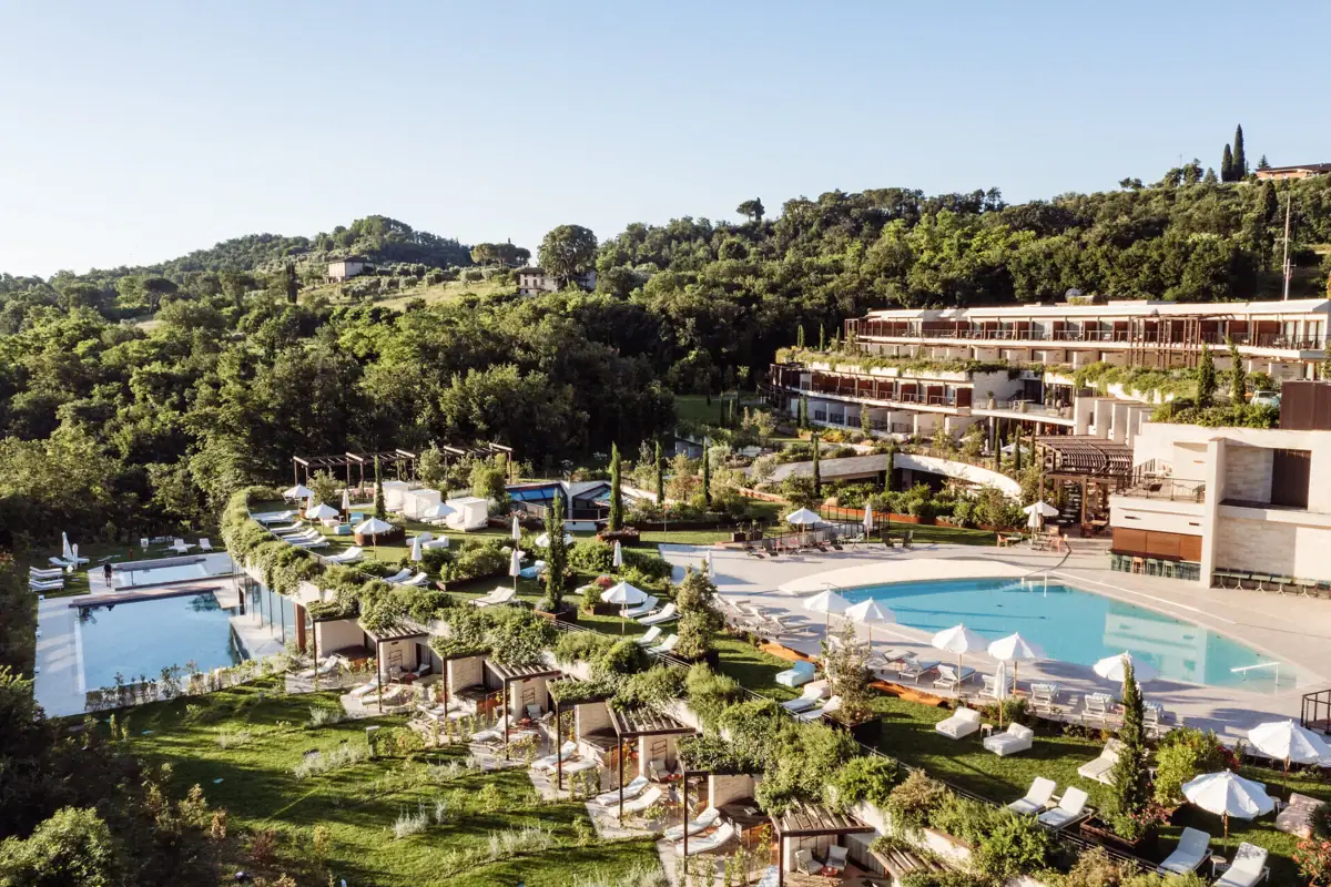 Blick auf den weitläufigen Pool- und Gartenbereich des A-ROSA Gardasee, eingebettet in mediterrane Hügellandschaft – ideal für Firmenfeiern und Incentives.