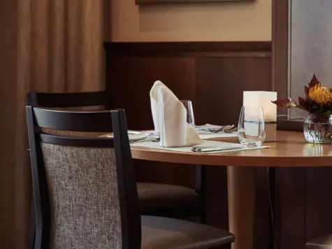 Elegantly laid table with napkins, glasses and a vase in the dining room.