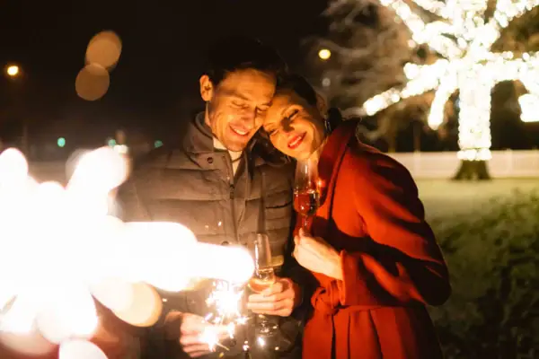 Ein Mann und eine Frau halten Weingläser und lächeln einander an.