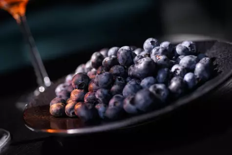 A dark plate of fresh blueberries.