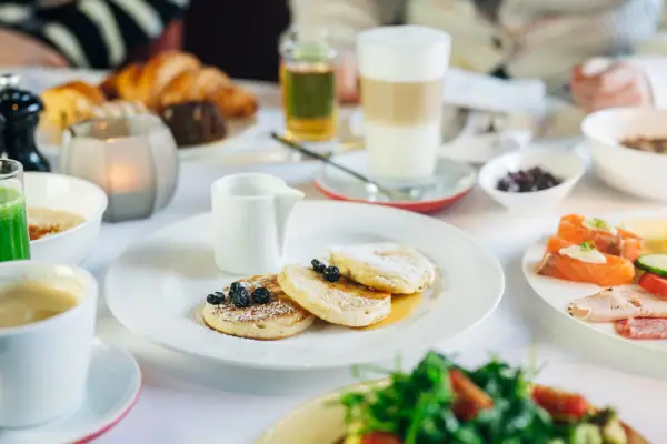Ein Teller mit Pfannkuchen, garniert mit Blaubeeren und Puderzucker.