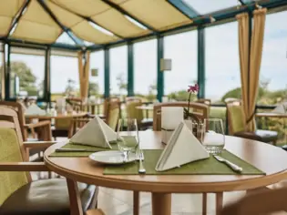 Elegantly laid table in a restaurant with crockery and tablecloth.