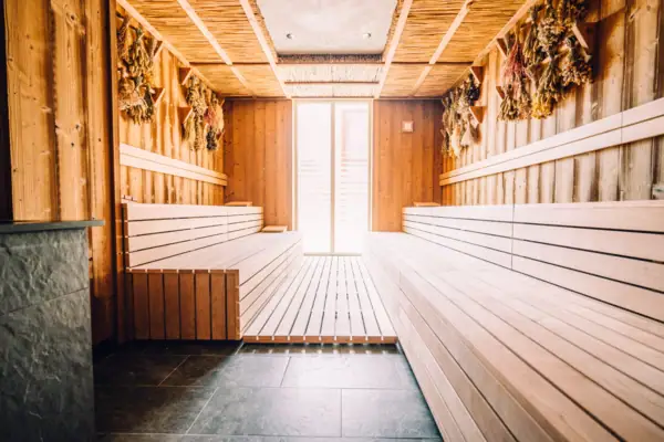 Reet- und Kräutersauna Ein Raum mit Holzbänken und einer Tür.