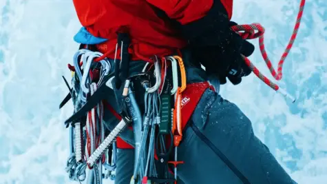 Many tools and equipment hang from carabiners around a person's waist.