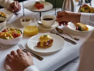 A breakfast table with fruit salad and egg dishes as well as coffee and orange juice.