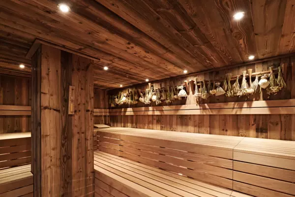 A wooden sauna with illuminated interior, featuring hardwood floors and ceiling.