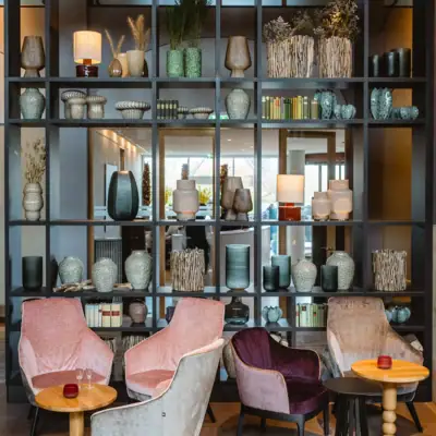A room with a shelf full of vases and chairs.