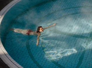 A woman swims in a warm, steaming pool.