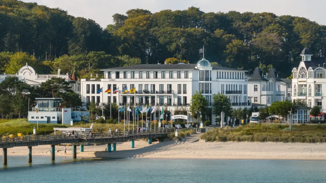 Buildings with flags and a bridge over a body of water.