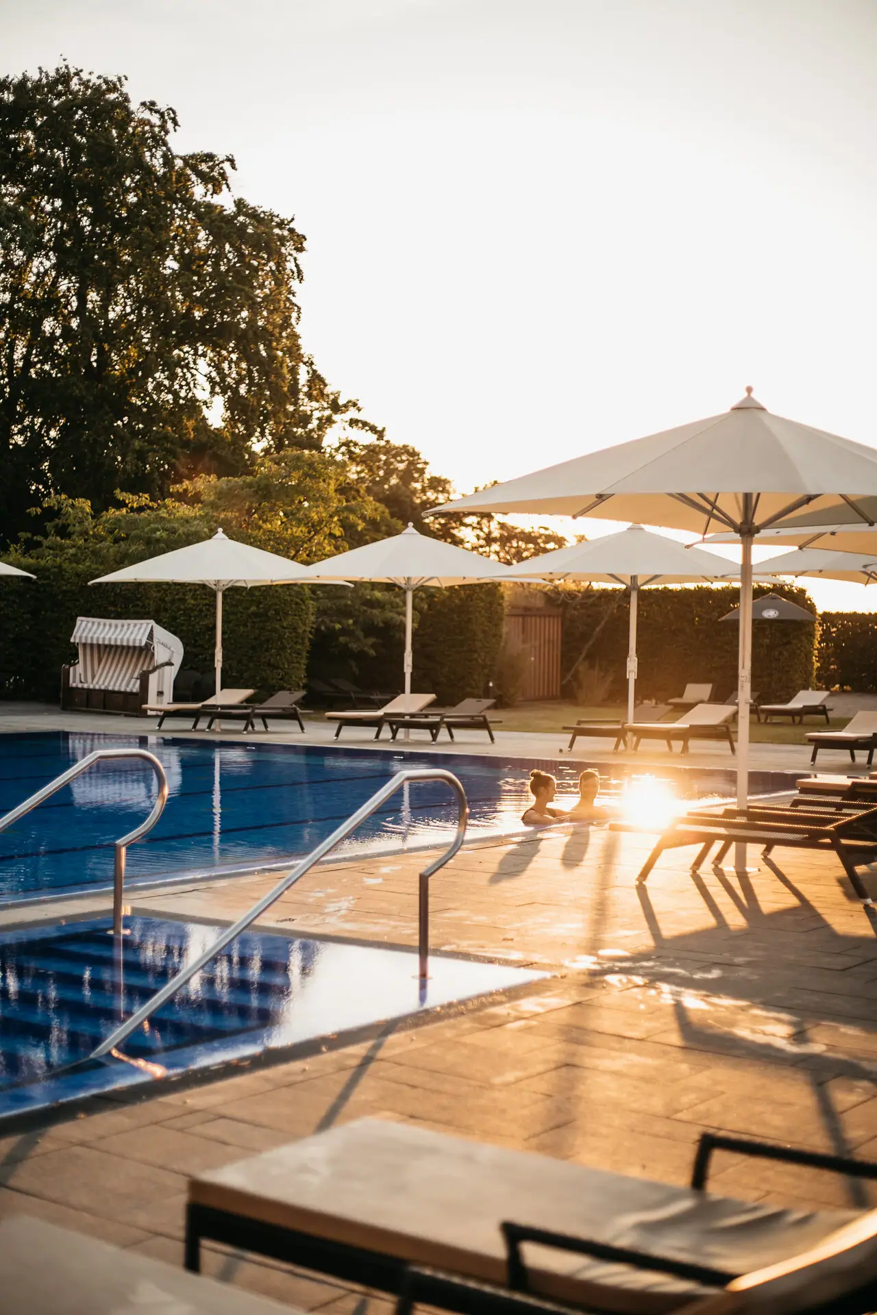An outdoor pool with parasols and deckchairs.