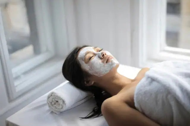 Eine Frau liegt mit einer weißen Maske auf dem Gesicht.