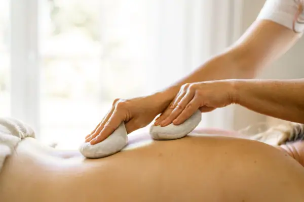 Frau erhält entspannende Signature Massage mit warmen Kompressen im A-ROSA Wellnessbereich am Gardasee.