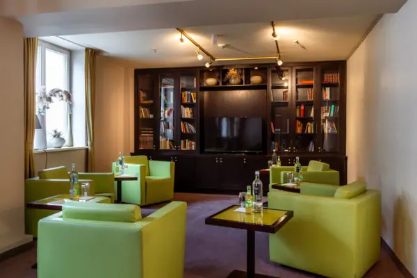 A room at the A-ROSA Travemünde with green armchairs and a television.