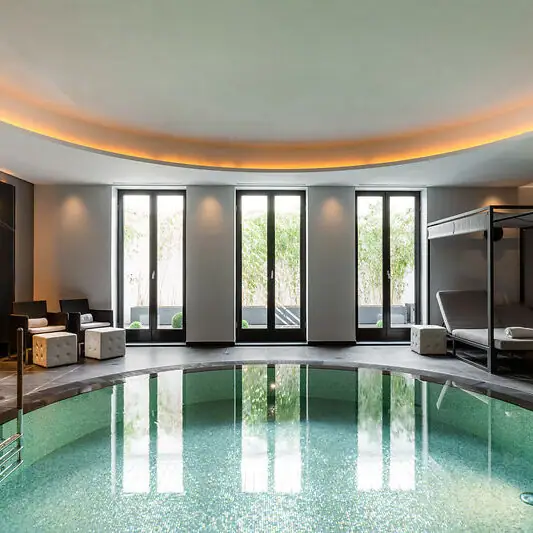 Indoor pool area with a bed and chairs.