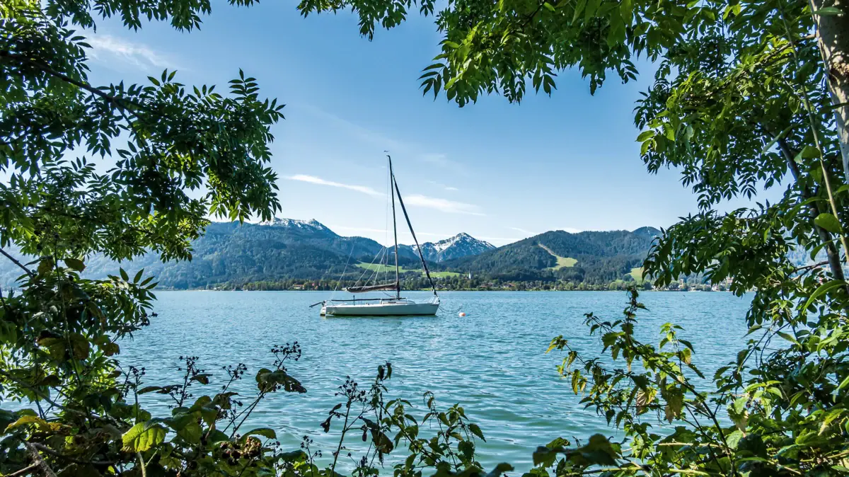 A boat on Lake Tegernsee with mountains in the background.
