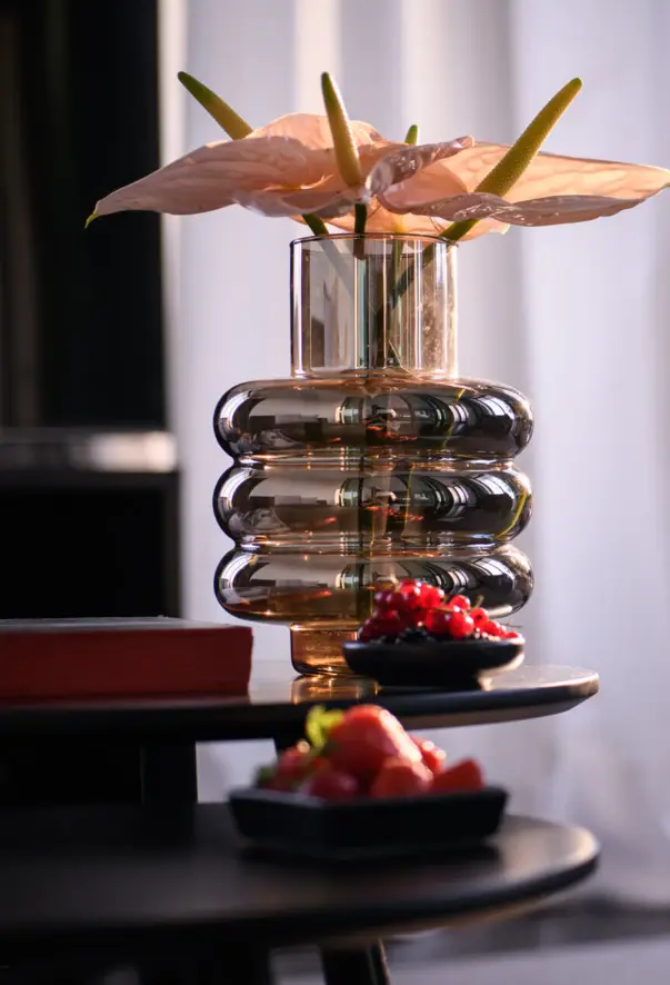 A vase with flowers on a coffee table in a well-furnished room.