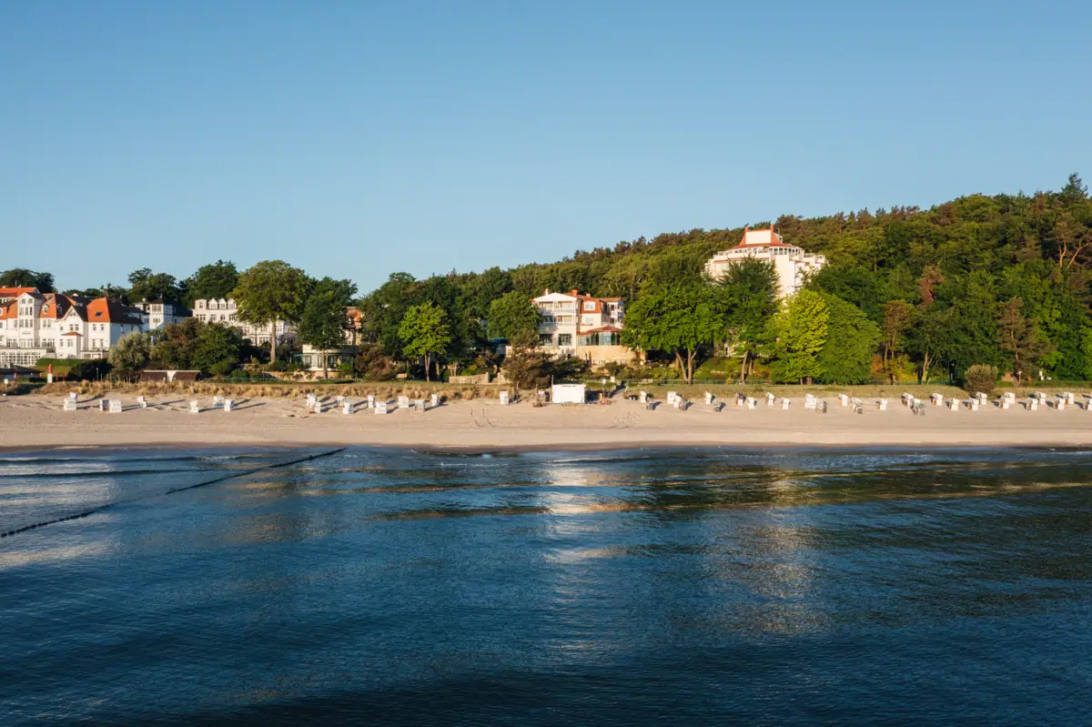 Ein Strand mit weißen Gebäuden und Bäumen.