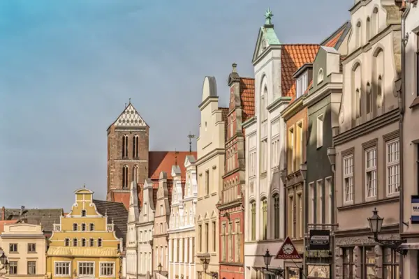 A row of buildings with a church tower standing out in the open.