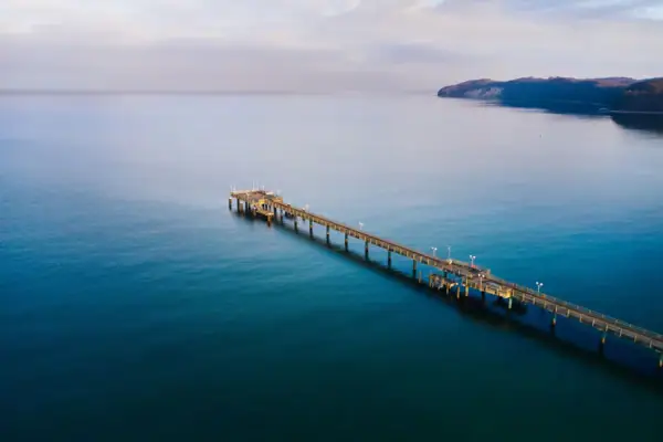 A long dock extending into a body of water under a cloudy sky.
