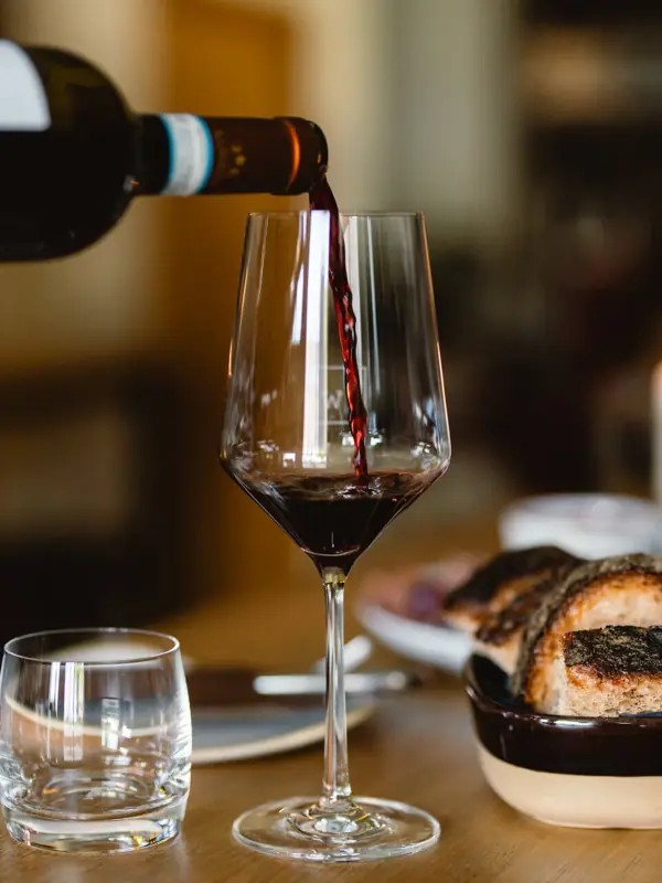 A person pours wine into a glass.