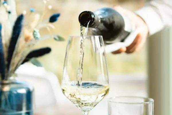 Eine Person gießt Wein in ein Glas.