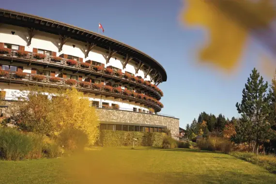 Round building in alpine style with many flower boxes under a blue sky.