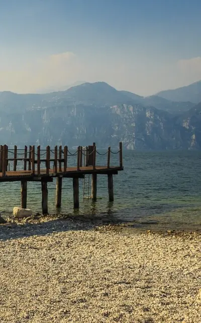 Wooden bridge over a body of water in a foggy mountain landscape.