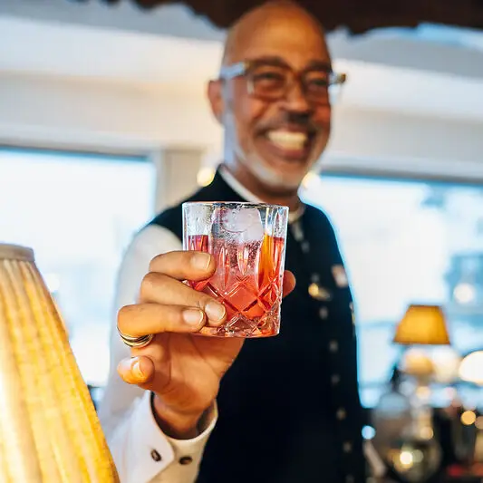 Man holding a cocktail and smiling indoors.