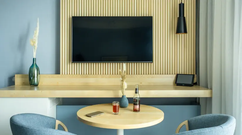 A table with a TV and another table with chairs in a living room.