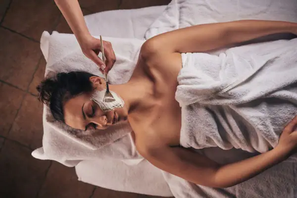 Woman lies with a face mask on her face.