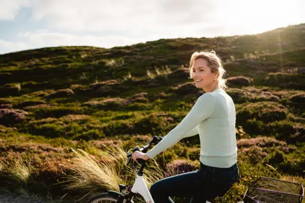 A woman is cycling amongst the dunes on Sylt.