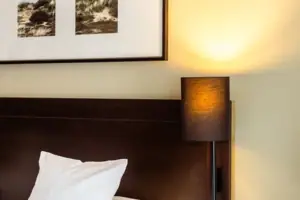 A bed with a lamp and a picture on the wall.