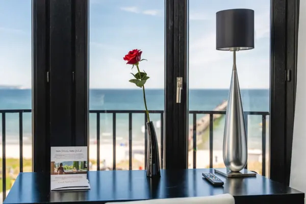 View of the beach from the hotel room through large windows, with visible sky and ocean.