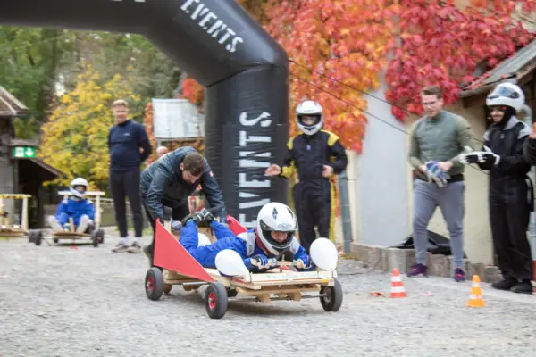 A group of people with helmets on a small wooden handcart.